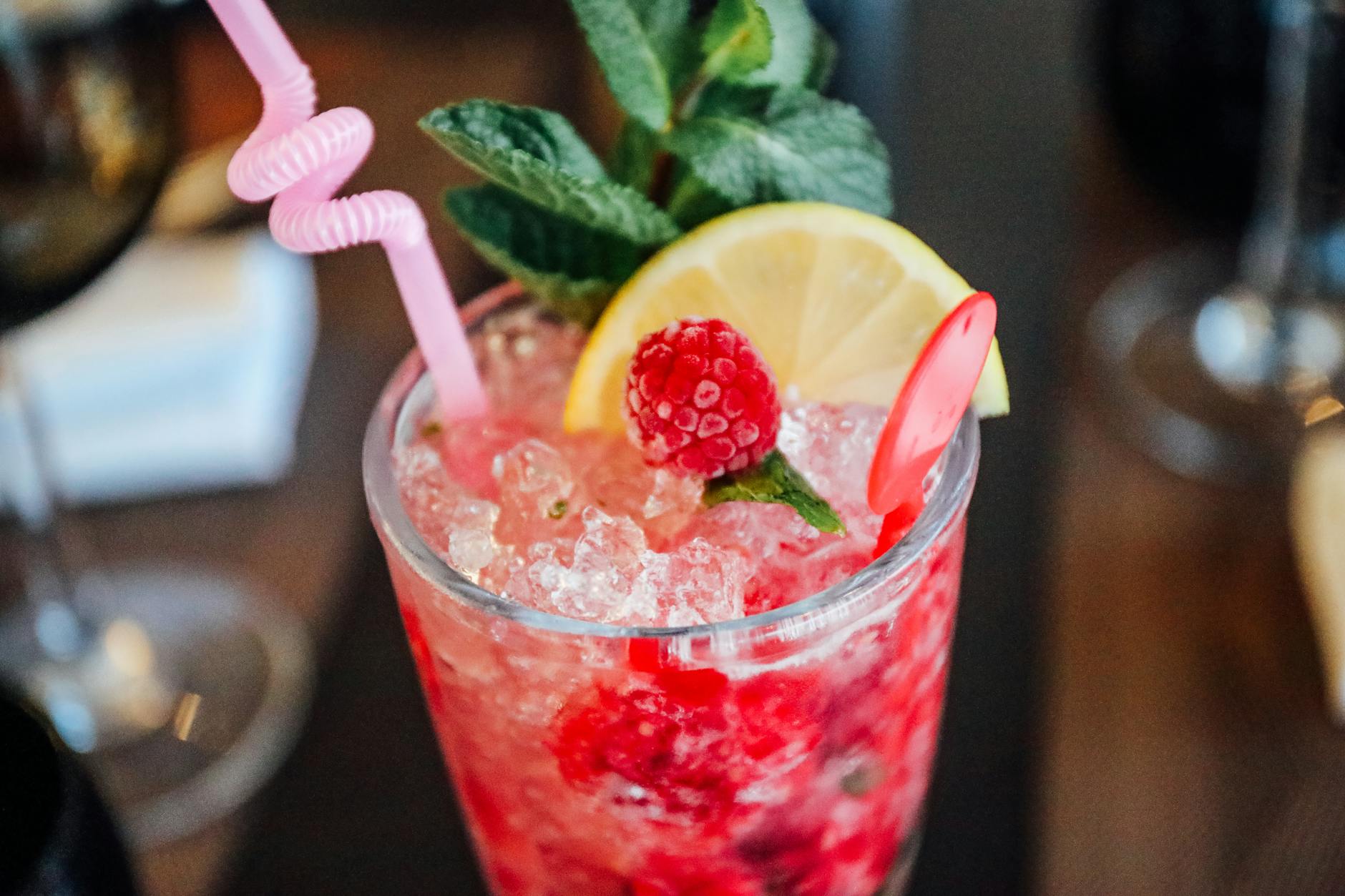 raspberry cold beverage with sliced lemon and mint
