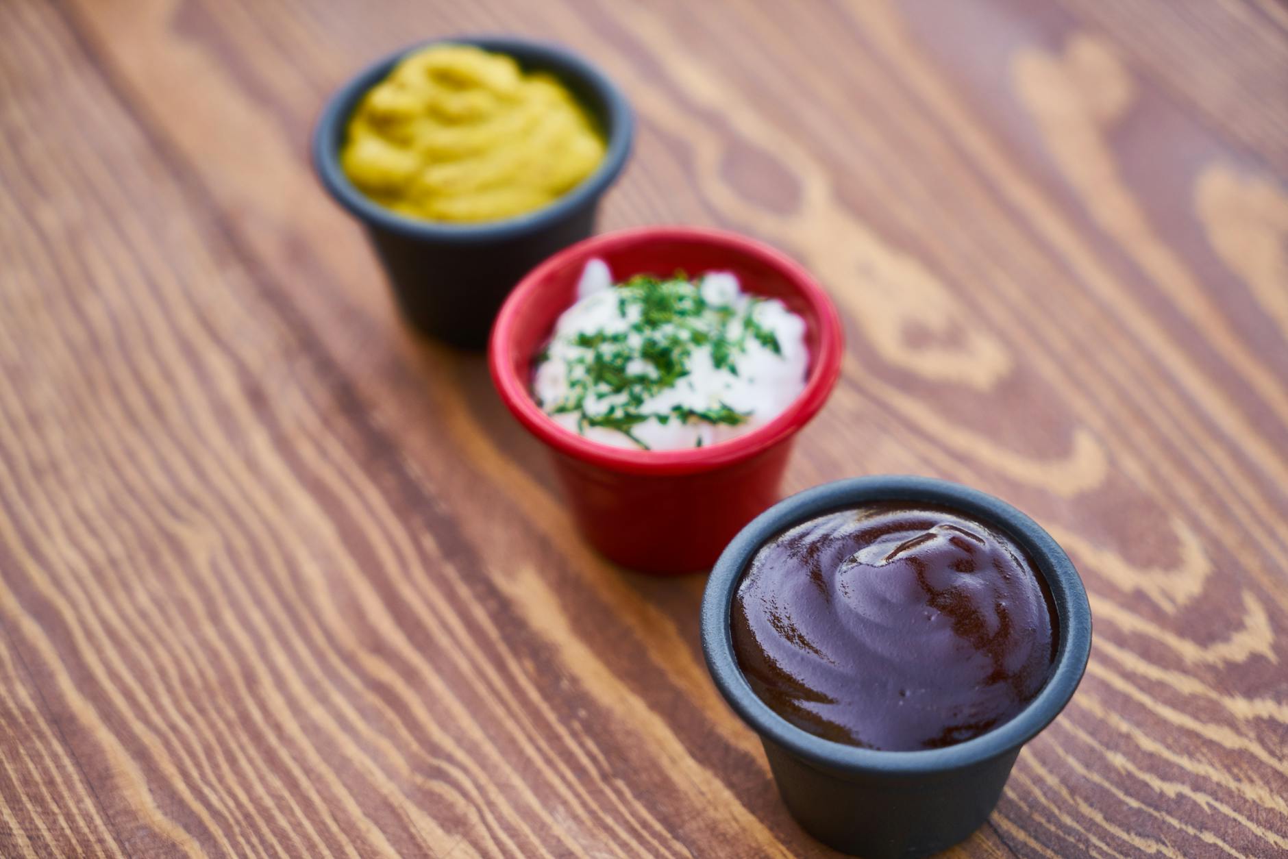 three assorted color of cream in containers on brown wooden slab