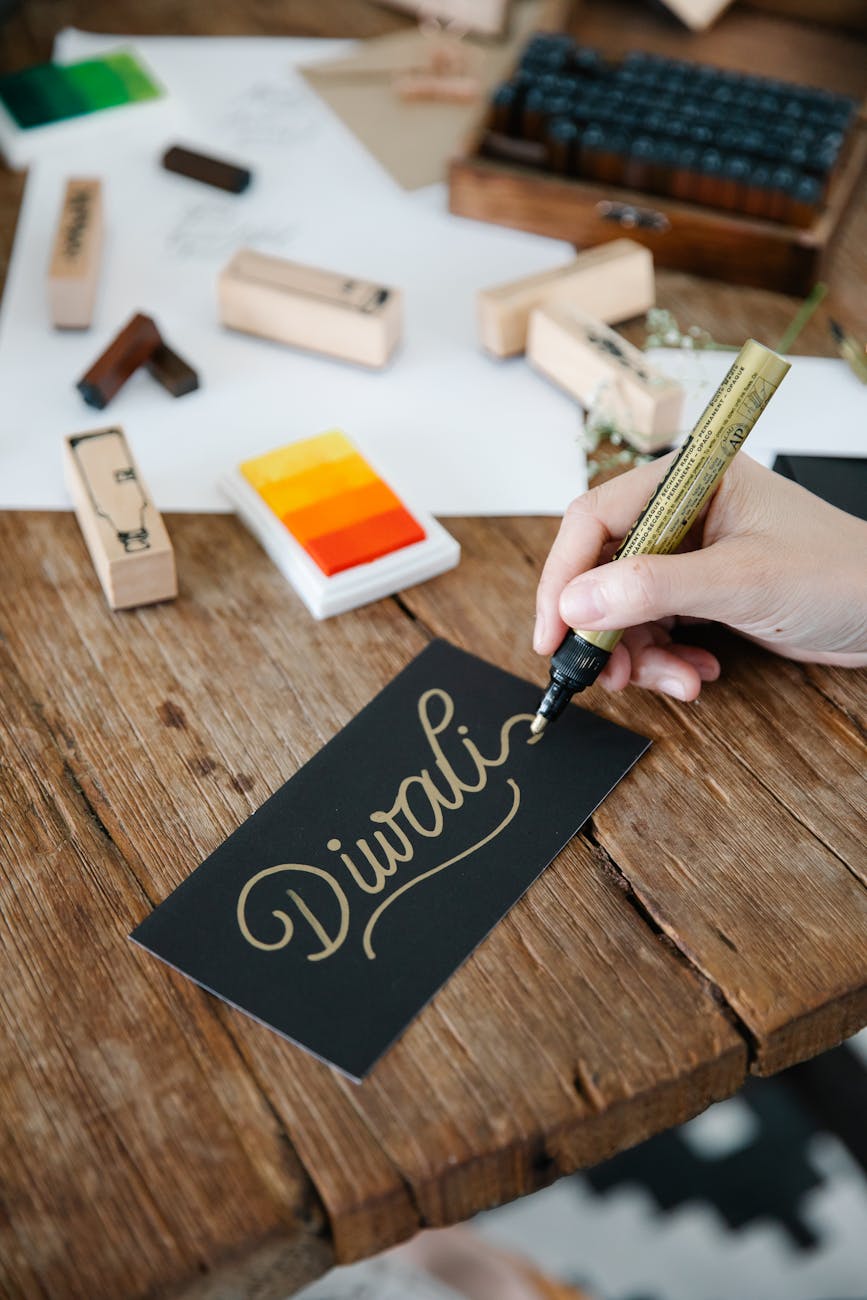a person writing diwali on black paper